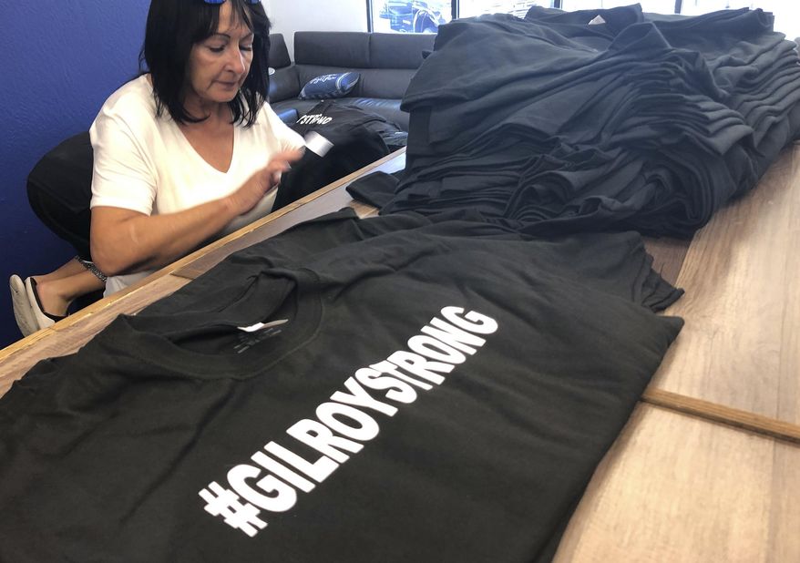 FILE - In this July 30, 2019 file photo, Rita Vadnais works at selling "#GilroyStrong" T-shirts, with proceeds benefiting shooting victims, at Windermere Real Estate in Gilroy, Calif., after a gunman killed two children and a 25-year-old at the Gilroy Garlic Festival the previous weekend. (AP Photo/Haven Daley, File)