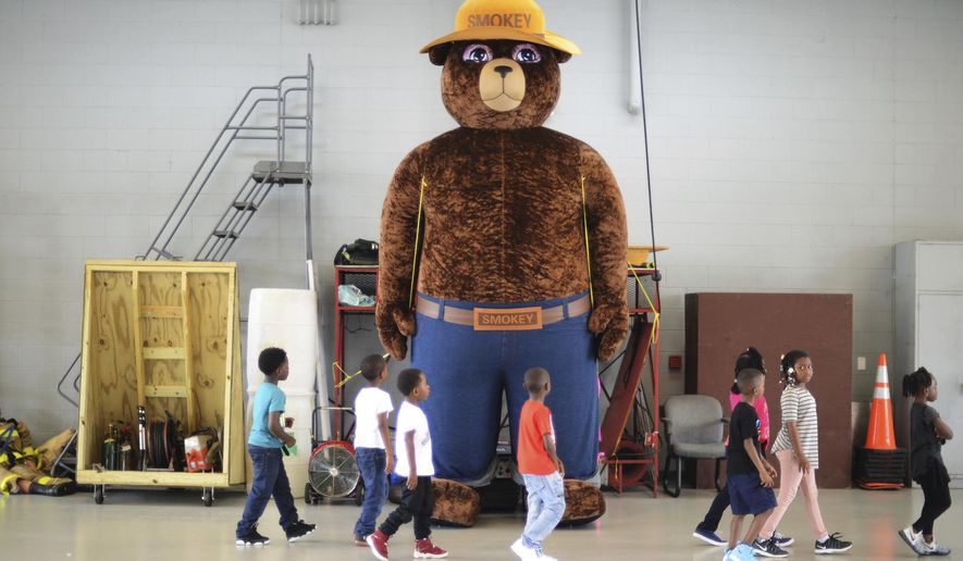 FILE - In this Wednesday, Oct. 11, 2017 file photo, a giant Smokey Bear statue greets children at the Fire Department Open House at Fire Station One in Kinston, N.C. The icon of the longest-running public service campaign in the U.S., was born on Aug. 9, 1944, when the U.S. Forest Service and the Ad Council agreed that a fictional bear would be the symbol for a fire prevention campaign. (Janet S. Carter/Daily Free Press via AP)