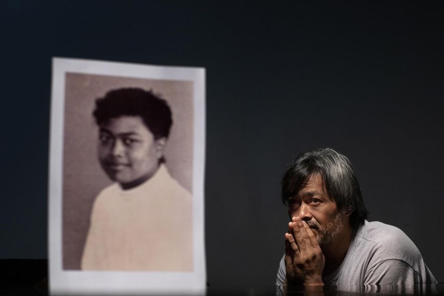 Mark Apuron, 45, sits beside a photo of himself when he was 15 years old, the age when he says he was raped by his uncle, former Archbishop Anthony Apuron at the rectory, in Hagatna, Guam, Monday, May 13, 2019. "Everything happened so fast," he recalls. "But that one second, for me, it never stops." He never found the right words to tell his parents what happened. "I didn't think I would be believed," he said, tearing up. "I thought I was the only one." Anthony Apuron denies the allegations, which are detailed in a lawsuit. (AP Photo/David Goldman)