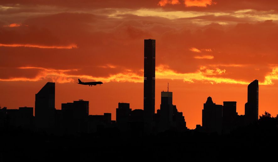 FILE - In this Sept. 6, 2016, file photo, a plane flies near the Manhattan skyline at sunset in New York. The latest mass shootings in the United States have triggered multiple countries to warn their citizens to be wary of travel conditions there. (AP Photo/Darron Cummings, File)