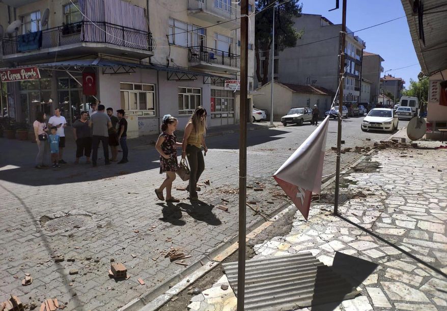 Minor damage, from an earthquake is seen on a street as residents stay out of buildings and on streets in Bozkurt, in Denizli province, west Turkey, Thursday, Aug. 8, 2019. The earthquake with an estimated magnitude of 6.0 hit western Turkey, damaging homes and causing some injuries, officials said. Bozkurt's mayor, Birsen Celik, told media that the quake knocked down two houses in the town but residents escaped with slight injuries. Several other homes were damaged with cracked walls. (Ramazan Cetin/DHA via AP)