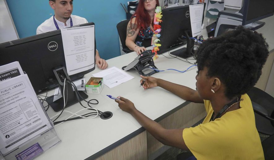 Shantel Johnson, right, a full time social worker at Queens Central Library, and Michael Montero, left, social work summer intern from NYU, meet at the library's coordinating desk for adult services, Monday July 29, 2019, in Queens borough of New York. Johnson oversees a team of case managers and help librarians connect visitors to social services. "You change with the times. I think every organization needs to do that in order to thrive," said Johnson. (AP Photo/Bebeto Matthews)