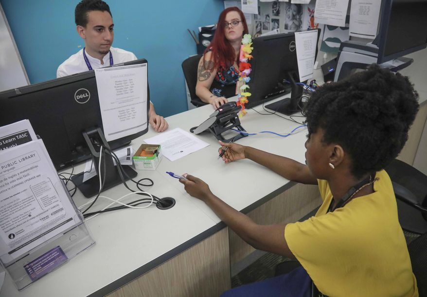 Shantel Johnson, right, a full time social worker at Queens Central Library, and Michael Montero, left, social work summer intern from NYU, meet at the library's coordinating desk for adult services, Monday July 29, 2019, in Queens borough of New York. Johnson oversees a team of case managers and help librarians connect visitors to social services. "You change with the times. I think every organization needs to do that in order to thrive," said Johnson. (AP Photo/Bebeto Matthews)