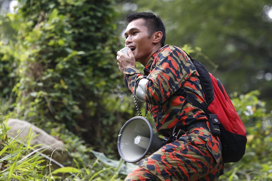 A member of a rescue team uses a loudspeaker as he conducts a search and rescue operation for a missing British girl at a forest in Seremban, Negeri Sembilan, Malaysia, Friday, Aug. 9, 2019. Police in Malaysia said on Thursday that they are using voice recordings conducted with the family of the 15-year old missing girl from London, in order to find her. (AP Photo/Lai Seng Sin)