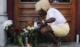 In this Aug. 4, 2019 photo Annette Gibson Strong places candles at a makeshift memorial for the slain and wounded at the scene of a mass shooting in Dayton, Ohio. Annette Gibson Strong started placing candles at a makeshift memorial the day of the shooting on Sunday. Strong says she’s continued to care for the memorial near Ned Peppers Bar in Dayton. It was outside the bar that Dayton police shot and killed the shooter as he approached the bar’s entrance. (AP Photo/John Minchillo)