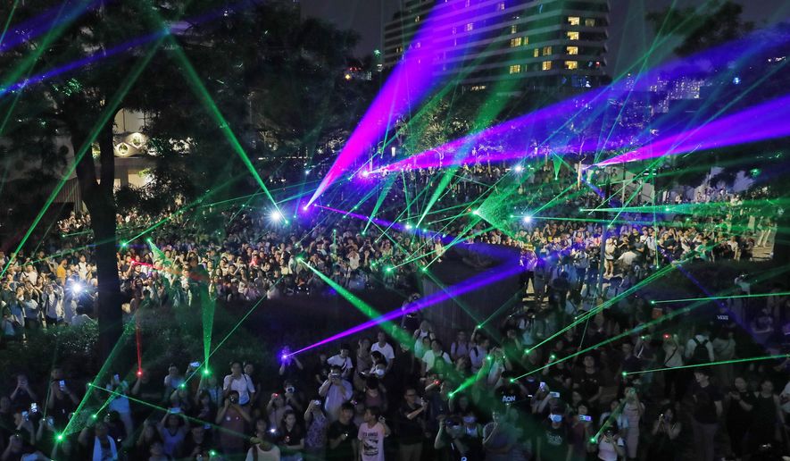 In this Aug. 7, 2019, photo, protesters use laser pointers during a rally to demonstrate against the arrests of people caught in possession of laser pointers that police classified as offensive weapons because of their ability to harm the eyes in Hong Kong. Hong Kong is facing its "most severe situation" since its handover from British rule in 1997 following weeks of demonstrations and the central government is considering what measures to take next, the head of Beijing's Cabinet office responsible for the territory said Wednesday. (AP Photo/Kin Cheung)