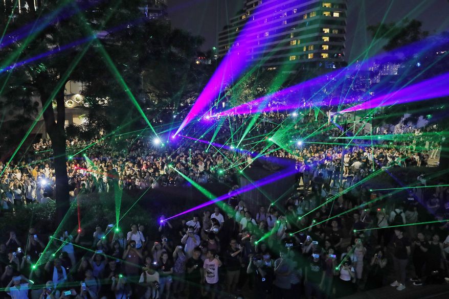 In this Aug. 7, 2019, photo, protesters use laser pointers during a rally to demonstrate against the arrests of people caught in possession of laser pointers that police classified as offensive weapons because of their ability to harm the eyes in Hong Kong. Hong Kong is facing its "most severe situation" since its handover from British rule in 1997 following weeks of demonstrations and the central government is considering what measures to take next, the head of Beijing's Cabinet office responsible for the territory said Wednesday. (AP Photo/Kin Cheung)