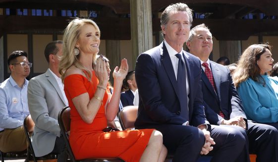 In this July 1, 2019 file photo First Partner Jennifer Siebel Newsom, left, attends a big signing ceremony with her husband, Gov. Gavin Newsom, right, at Sacramento City College in Sacramento, Calif. Siebel Newsom has shunned the traditional title of &amp;quot;first lady&amp;quot; and is focusing on women&#39;s issues including equal pay and expanding family leave. (AP Photo/Rich Pedroncelli, File)