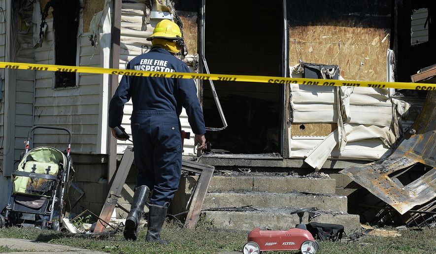 Erie Bureau of Fire Inspector Mark Polanski helps investigate a fatal fire at 1248 West 11th St. in Erie, Pa, on Sunday, Aug. 11, 2019. Authorities say an early morning fire in northwestern Pennsylvania claimed the lives of multiple children and sent another person to the hospital. (Greg Wohlford/Erie Times-News via AP)