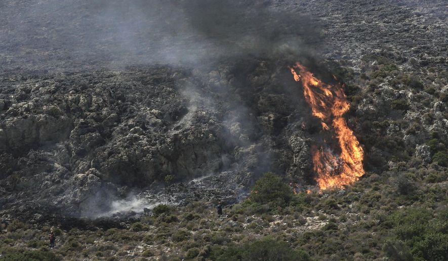 Firefighters approach a wildfire at Elafonisos island, south of Peloponnese peninsula, on Saturday, Aug. 10, 2019. A wildfire which broke out on Elafonisos island in southern Greece on Saturday has prompted the evacuation of a hotel and camping as a precautionary measure, with no injuries reported, according to Greek national news agency AMNA. (AP Photo/Nikolia Apostolou)