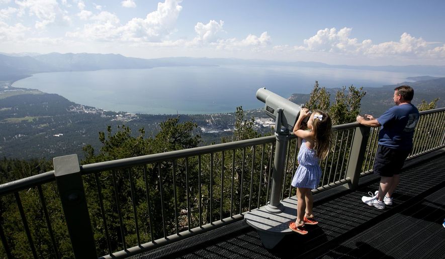 FILE - In this Aug. 8, 2017, file photo, Lilyana Allen, of Guam, uses a telescope to view Lake Tahoe from an observation platform at the Heavenly Mountain Resort during a family visit to South Lake Tahoe, Calif. A new report on the progress of efforts to protect Lake Tahoe says removing an invasive shrimp from the mountain waters could offset a decline in clarity and other damage from human-caused global warming. (AP Photo/Rich Pedroncelli, File)