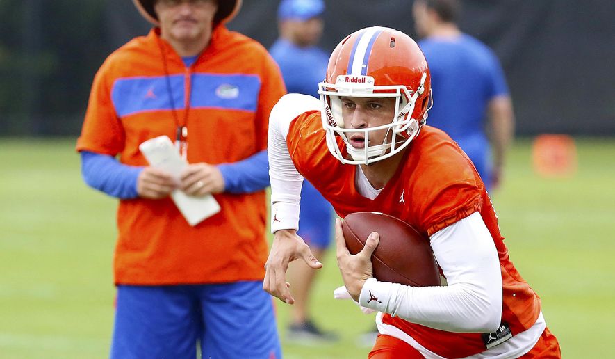 FILE - In this July 26, 2019, file photo, Florida quarterback Feleipe Franks (13) runs with the ball as head coach Dan Mullen watches during an NCAA college football practice in Gainesville, Fla. (Brad McClenny/The Gainesville Sun via AP, File)