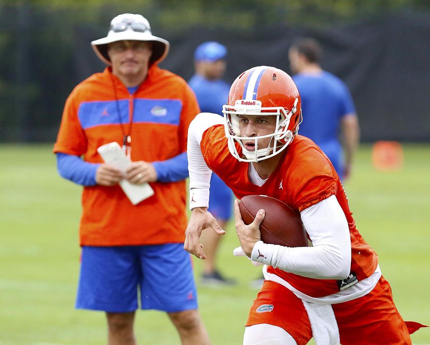 FILE - In this July 26, 2019, file photo, Florida quarterback Feleipe Franks (13) runs with the ball as head coach Dan Mullen watches during an NCAA college football practice in Gainesville, Fla. (Brad McClenny/The Gainesville Sun via AP, File)