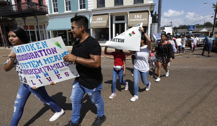 FILE - In this Aug. 11, 2019 photo, children of mainly Latino immigrant parents hold signs in support of them and those individuals picked up during an immigration raid at a food processing plant in Canton, Miss., following a Spanish Mass at Sacred Heart Catholic Church in Canton, Miss. Trump administration rules that could deny green cards to immigrants if they use Medicaid, food stamps, housing vouchers or other forms of public assistance are going into effect. (AP Photo/Rogelio V. Solis)