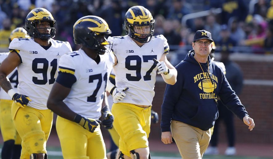 FILE- In an April 13, 2019, file photo, Michigan head coach Jim Harbaugh walks out with players during the team's annual spring NCAA college football game in Ann Arbor, Mich. Harbaugh seems to be set up for success at Michigan in his fifth season, leading a program that is a popular choice to win the Big Ten. "That's where I would pick us," Harbaugh said. Some are predicting the Wolverines will earn a spot in the College Football Playoff to give them a chance to win a national championship for the first time since 1997. (AP Photo/Carlos Osorio, File)