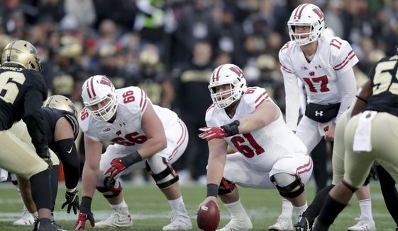 FILE - In this Nov. 17, 2018, file photo, Wisconsin&#39;s Tyler Biadasz (61) gestures as he prepares to snap the ball to quarterback Jack Coan during the first half against Purdue in an NCAA college football game in West Lafayette, Ind. Returning starting center  Biadasz, who underwent hip surgery during the offseason, will anchor the line after earning first-team All-Big Ten honors in 2018. (AP Photo/Michael Conroy, File)