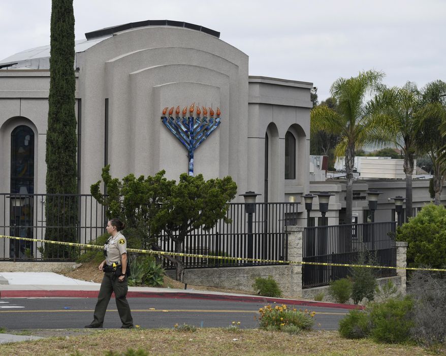 FILE - In this Sunday, April 28, 2019 file photo, a San Diego county sheriff's deputy stands in front of the Chabad of Poway synagogue, in Poway, Calif. A 19-year-old nursing student who opened fire at the California synagogue in April didn't have a valid hunting license, which is the only way someone under 21 who isn't in the military or law enforcement can legally buy a weapon under state law. The California Fish and Wildlife Department said Wednesday, Aug. 14, 2019, that John T. Earnest was issued a hunting license, but it had not gone into effect yet. It’s unclear how Earnest bought the gun. (AP Photo/Denis Poroy, File)