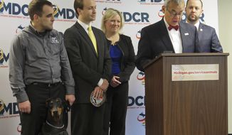 FILE - In this Wednesday, Jan. 13, 2016 file photo, Michigan Department of Civil Rights Director Agustin Arbulu, second right, speaks about a new service animal law in Lansing, Mich. Then Lt. Gov. Brian Calley, left, carries a patch that people with service animals will be able to obtain for free from the state to affix to their animal&#39;s vest. Michigan Gov. Gretchen Whitmer said Wednesday, Aug. 14, 2019, that Arbulu should resign or be fired after he made inappropriate, offensive comments about women. (AP Photo/David Eggert, File)