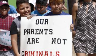 FILE - In this Aug. 11, 2019, file photo, children of mainly Latino immigrant parents hold signs in support of them and those individuals picked up during an immigration raid at a food processing plant, during a protest march to the Madison County Courthouse in Canton, Miss. Unauthorized workers are jailed or deported, while the managers and business owners who profit from their labor often aren’t. Under President Donald Trump, the numbers of owners and managers facing criminal charges for employing unauthorized workers have stayed almost the same. (AP Photo/Rogelio V. Solis, File)