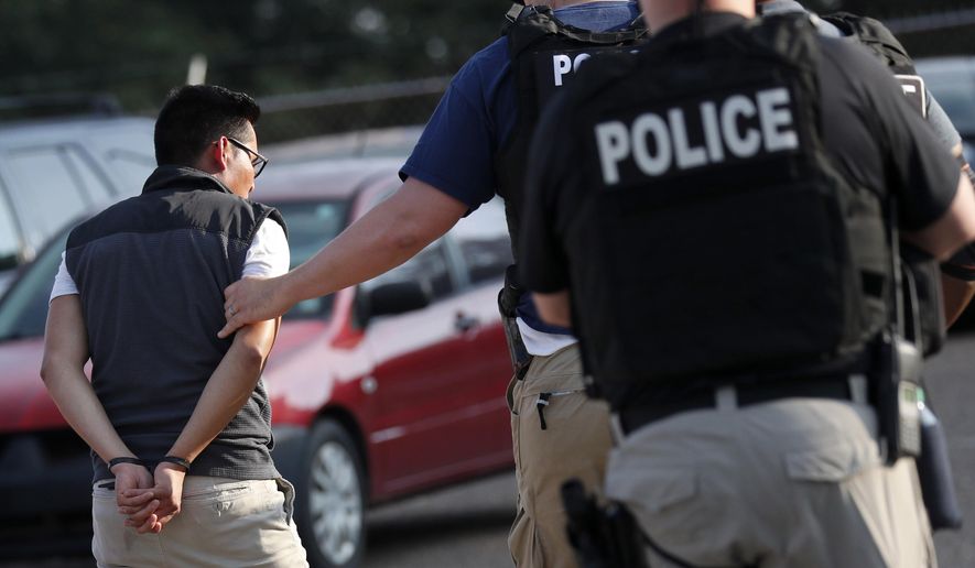 FILE - In this Aug. 7, 2019, file photo, a man is taken into custody at a Koch Foods Inc. plant in Morton, Miss. Unauthorized workers are jailed or deported, while the managers and business owners who profit from their labor often aren't. Under President Donald Trump, the numbers of owners and managers facing criminal charges for employing unauthorized workers have stayed almost the same. (AP Photo/Rogelio V. Solis, File)