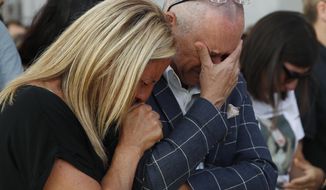 Relatives of the victims of the Morandi bridge collapse, cry during a remembrance ceremony to mark the first anniversary of the tragedy, in Genoa, Italy, Wednesday, Aug. 14, 2019. The Morandi bridge was a road viaduct on the A10 motorway in Genoa, that collapsed one year ago killing 43 people. (AP Photo/Antonio Calanni)