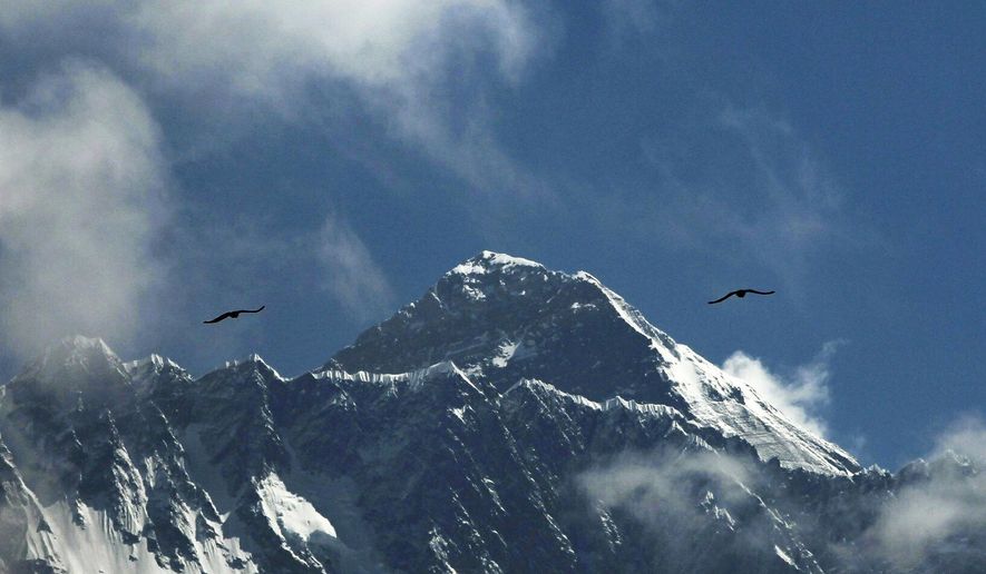 FILE - In this May 27, 2019, file photo, birds fly as Mount Everest is seen from Namche Bajar, Solukhumbu district, Nepal. A Nepal government committee formed after a bad mountaineering season on Mount Everest has recommended new rules that would require climbers to have scaled tall peaks, undergone proper training, and possess certificates of good health and insurance that would cover rescue costs if required. A report by the committee released Wednesday, Aug. 15, says people must have successfully climbed a peak higher than 6,500 meters (21,320 feet) before they can apply for a permit to scale Mount Everest. Each climber would also be required to have a highly experienced guide. (AP Photo/Niranjan Shrestha, File)
