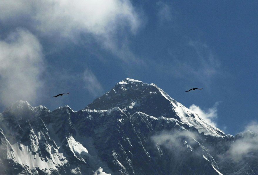 FILE - In this May 27, 2019, file photo, birds fly as Mount Everest is seen from Namche Bajar, Solukhumbu district, Nepal. A Nepal government committee formed after a bad mountaineering season on Mount Everest has recommended new rules that would require climbers to have scaled tall peaks, undergone proper training, and possess certificates of good health and insurance that would cover rescue costs if required. A report by the committee released Wednesday, Aug. 15, says people must have successfully climbed a peak higher than 6,500 meters (21,320 feet) before they can apply for a permit to scale Mount Everest. Each climber would also be required to have a highly experienced guide. (AP Photo/Niranjan Shrestha, File)