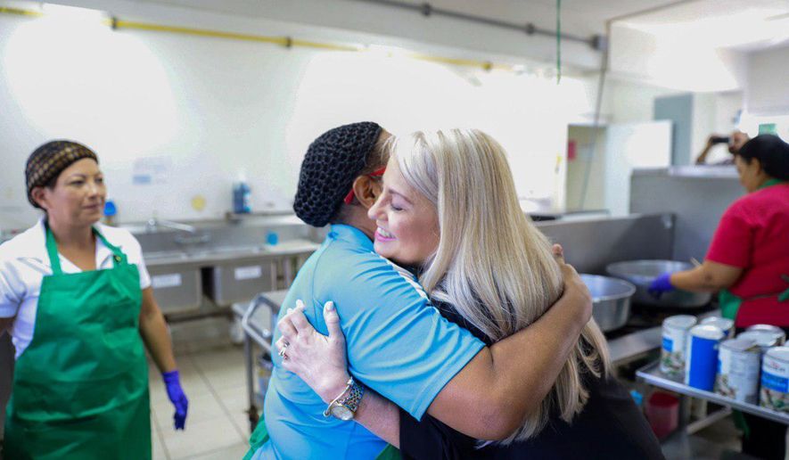 In this handout photo provided by the Governor's Office, Puerto Rico Gov. Wanda Vazquez embraces a cafeteria worker during a visit to the Ramon Marin Sola School, in Guaynabo, Puerto Rico, Monday, Aug. 12, 2019. Vazquez visited the elementary school she attended as a child, marking the beginning of the 2019-2020 school year. (Governor's Office via AP)