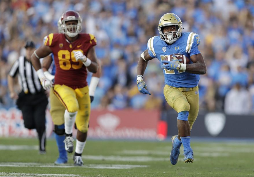 FILE - In this Nov. 17, 2018, file photo, UCLA running back Joshua Kelley, right, runs for a touchdown against Southern California during the second half of an NCAA college football game in Pasadena, Calif. The offense returns nine starters, including sophomore quarterback Dorian Thompson-Robinson and senior running back Joshua Kelley, who went for 289 yards in the victory over USC. (AP Photo/Marcio Jose Sanchez, File)