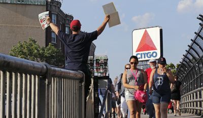 In this Wednesday, June 1, 2016, file photo, a hawker sells programs, with the iconic Citgo sign in the background, as fans walk from Kenmore Square to a baseball game at Fenway Park in Boston. The Boston Landmarks Commission meets Tuesday to decide whether to launch a study to determine if the sign qualifies for preservation as a historic landmark. Thousands of Bostonians have signed a petition clamoring to save it. (AP Photo/Charles Krupa) ** FILE **