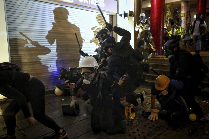 In this Aug. 11, 2019, photo, policemen charge towards protesters during the anti-extradition bill protest at Tsim Sha Tsui in Hong Kong. Police fired tear gas late Sunday afternoon to try to disperse a demonstration in Hong Kong as protesters took over streets in two parts of the Asian financial capital, blocking traffic and setting up another night of likely showdowns with riot police. (Eric Tsang/HK01 via AP)