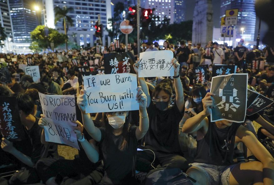 Pro-democracy protesters display placards during a rally organized by higher education students in Chater Garden in Hong Kong Friday, Aug. 16, 2019. China's paramilitary People's Armed Police marched and practiced crowd control tactics at a sports complex in Shenzhen across the border in Hong Kong on Friday, in what some have interpreted as a threat against pro-democracy protesters. (AP Photo/Kin Cheung)
