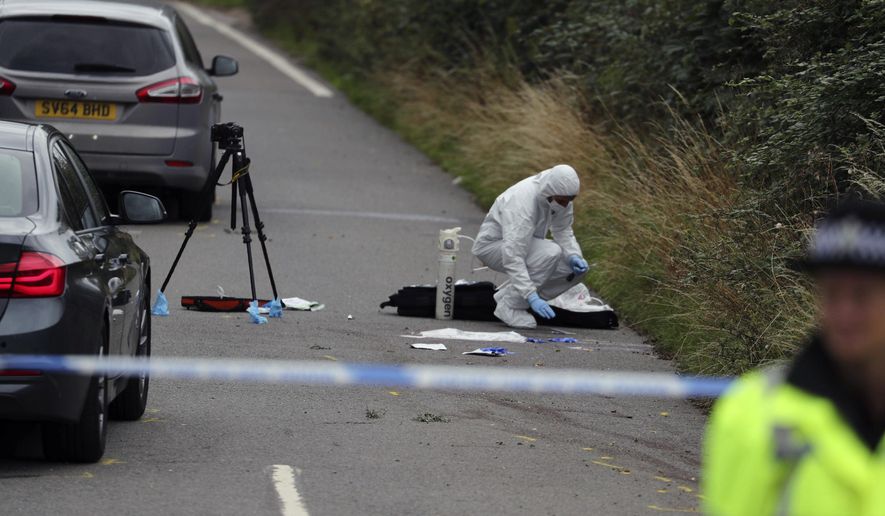 A police investigator at the scene of an incident where a police officer was killed, near Sulhamstead, England, Friday, Aug. 16, 2019. Thames Valley police say a British police officer investigating a reported burglary has been killed. Ten males have been arrested and are in custody, including a 13-year-old. Authorities say police Constable Andrew Harper of the Roads Policing Proactive unit was killed while "performing his duties" on Thursday night near the A4 between Reading and Newbury, in southeast England. (Steve Parsons/PA via AP)