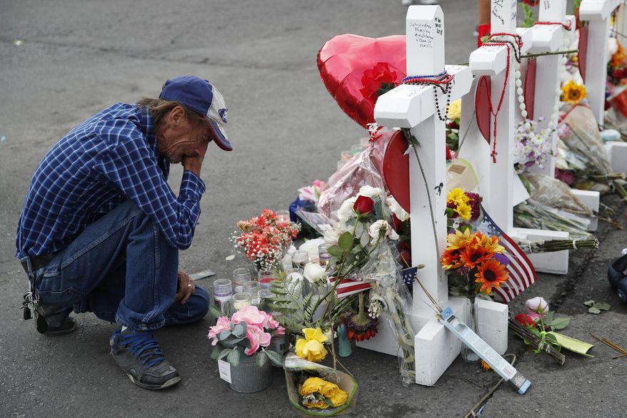 In this Aug. 6, 2019 file photo, Antonio Basco cries beside a cross at a makeshift memorial near the scene of a mass shooting at a shopping complex, in El Paso, Texas. Basco, whose 63-year-old wife was among the Texas mass shooting victims says he has no other family and welcomes anyone wanting to attend her services in El Paso. Margie Reckard was among 22 people fatally shot on Aug. 3 at a Walmart. Reckard and Basco were married 22 years. (AP Photo/John Locher, File)