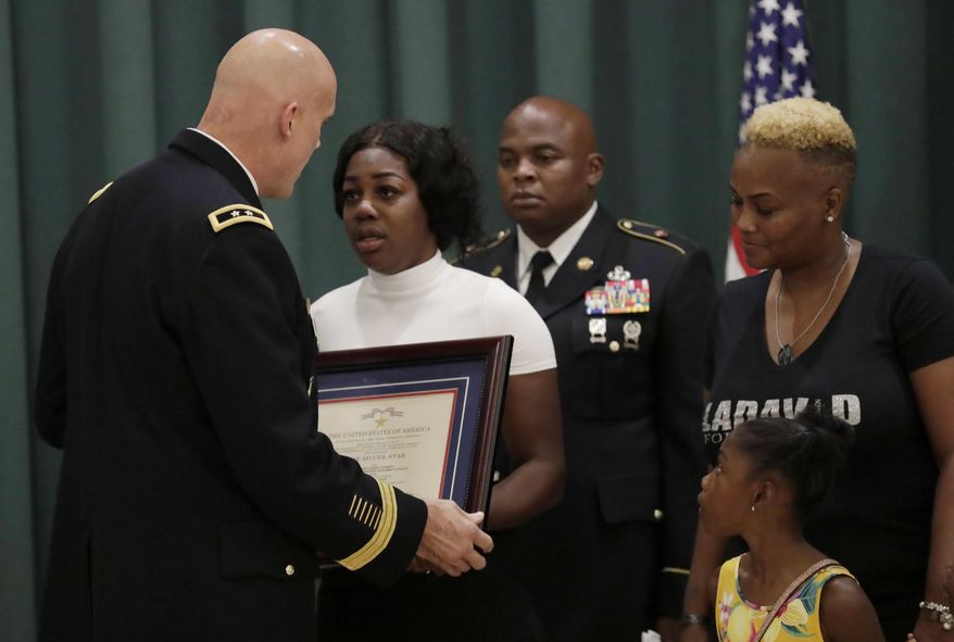 Maj. Gen. John Deedrick, left, presents a plaque to Myeshia Johnson, the widow of Sgt. LaDavid Johnson, during a ceremony awarding the Silver Star Medal to LaDavid Johnson, Friday, Aug. 16, 2019, in Miami Gardens, Fla. Johnson was killed in action during operations in Niger in 2017. At right is LaDavid Johnson's' mother Cowanda Jones- Johnson, and daughter Ahleesya. (AP Photo/Lynne Sladky)