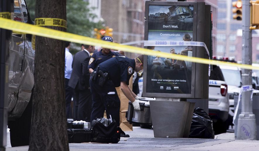 An investigator picks up a suspicious package that was thought to be an explosive device in Manhattan's Chelsea neighborhood Friday, Aug. 16, 2019, in New York. The appliance was deemed harmless and taken away as evidence. (AP Photo/Kevin Hagen).