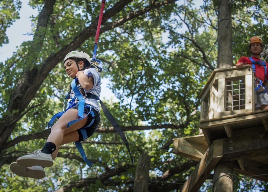 In this Aug. 8, 2019 photo, Girl Scout Mataya Wilcox leaps from 30 feet on a QuickFlight free fall device at Eugene's Adventure Course, named for the late Girl Scouts Spirit of Nebraska benefactor and outdoor enthusiast Eugene Catron, near Nebraska City, Neb. (Francis Gardler/Lincoln Journal Star via AP)