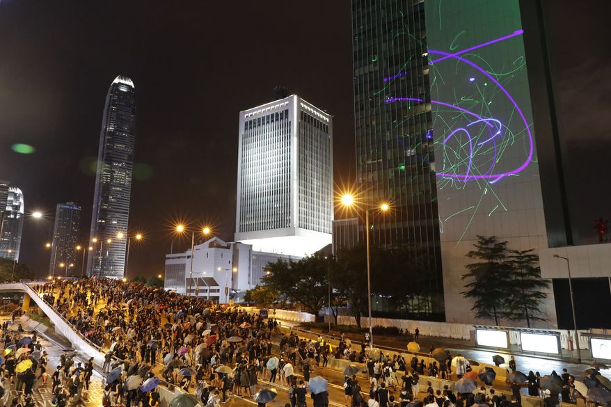 Protesters shine laser pointers on the Government Headquarters complex in Hong Kong, Sunday, Aug. 18, 2019. Heavy rain fell on tens of thousands of umbrella-toting protesters Sunday as they marched from a packed park and filled a major road in Hong Kong, where mass pro-democracy demonstrations have become a regular weekend activity over the summer. (AP Photo/Vincent Thian)