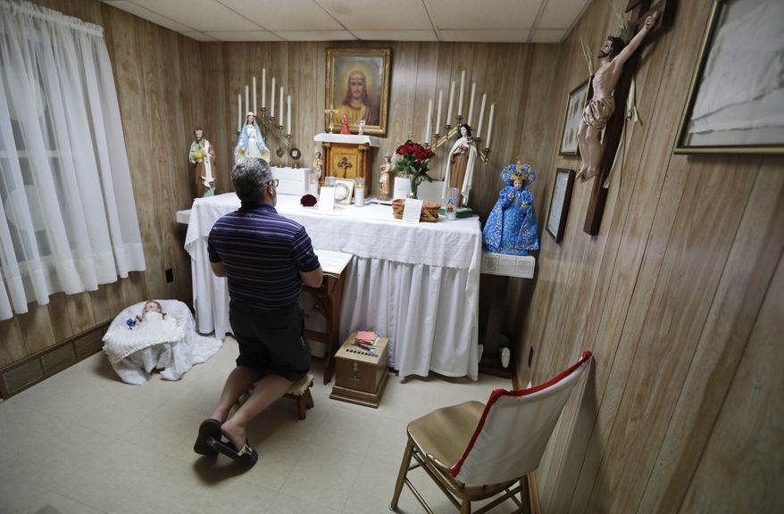 In this Aug. 9, 2019, photo Ron Sattler kneels and prays in front of the altar in Canton, Ohio. Late in the summer of 1939, crowds of strangers started showing up at Rhoda Wises house next to a city dump in Ohio after she let it be known that miracles were occurring in her room. Eight decades later, people still make pilgrimages to the wood frame bungalow at the edge of Canton, seeking their own miracles. (AP Photo/Tony Dejak)