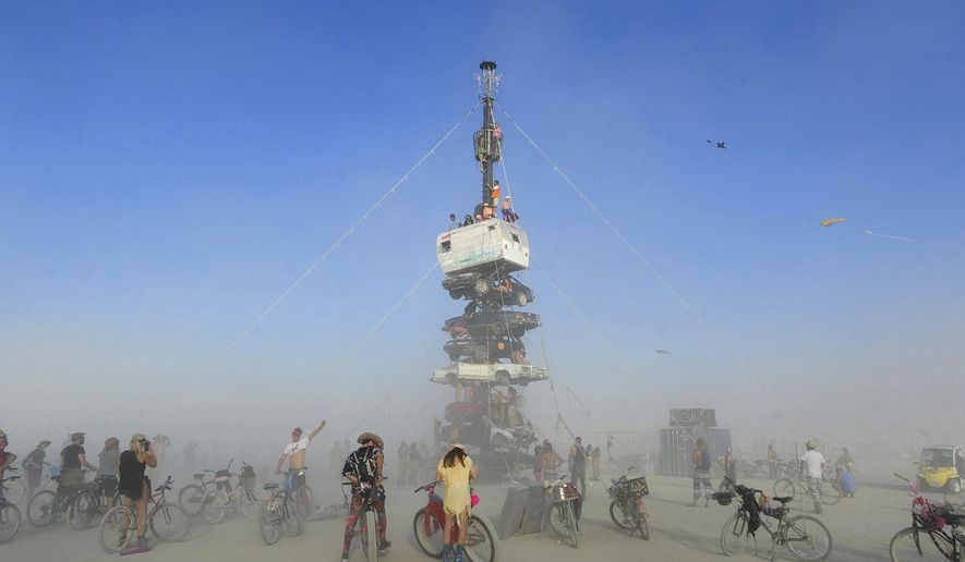 FILE -  this Monday, Aug. 27, 2018 file photo, burners surrounded by playa dust climb onto an art installation titled, &amp;quot;Night of the Climb,&amp;quot; at Burning Man, in Gerlach, Nev. Experts say playa dust doesn&#x27;t pose any significant health risk to those who inhale it during the annual counter-culture festival in the desert. (Andy Barron/The Reno Gazette-Journal via AP, File)