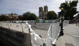 A vacuum cleaner stands amid protection panels securing a perimeter around the Notre Dame Cathedral ahead of the start of a massive lead decontamination in Paris, Friday, Aug. 16, 2019. (AP Photo/Francois Mori)
