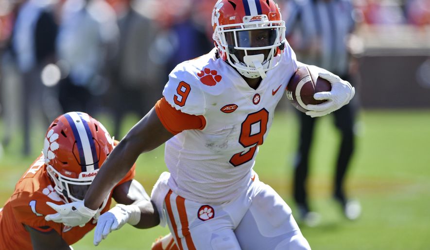 FILE - In this April 6, 2019, file photo, Clemson's Travis Etienne (9) rushes out of the tackle attempt by Derion Kendrick during Clemson's annual Orange and White NCAA college football spring scrimmage in Clemson, S.C. Etienne is one of three Clemson Tigers selected an AP preseason All-American along with quarterback Trevor Lawrence and linebacker Isaiah Simmons. (AP Photo/Richard Shiro, File)