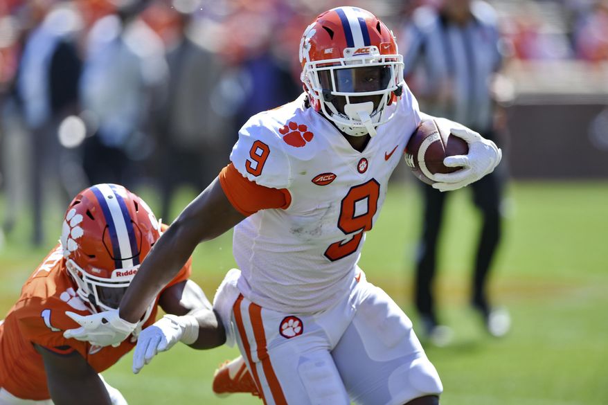 FILE - In this April 6, 2019, file photo, Clemson's Travis Etienne (9) rushes out of the tackle attempt by Derion Kendrick during Clemson's annual Orange and White NCAA college football spring scrimmage in Clemson, S.C. Etienne is one of three Clemson Tigers selected an AP preseason All-American along with quarterback Trevor Lawrence and linebacker Isaiah Simmons. (AP Photo/Richard Shiro, File)