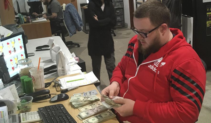 FILE - In this Wednesday, Dec. 27, 2017, file photo employee Joshua Wilson counts cash at the Golden State Greens marijuana dispensary in San Diego.The California Supreme Court has ruled San Diego failed to adequately analyze the potential environmental impacts of its marijuana dispensary law. (AP Photo/Elliot Spagat,File)