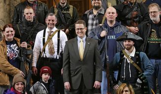 FILE - In this Jan. 15, 2015, file photo, Washington state Rep. Matt Shea, R-Spokane Valley, center, poses for a group photo with gun owners inside the Capitol in Olympia, Wash., following a gun-rights rally. The mayor and police chief of Spokane, Wash., are the latest to demand that the conservative state legislator resign from office after leaked emails revealed he sought to conduct surveillance on local progressive leaders. Mayor David Condon and Police Chief Craig Meidl on Tuesday, Aug. 20, 2019 denounced Shea, who wants to create a 51st state based on Christian principles.(AP Photo/Ted S. Warren, File)