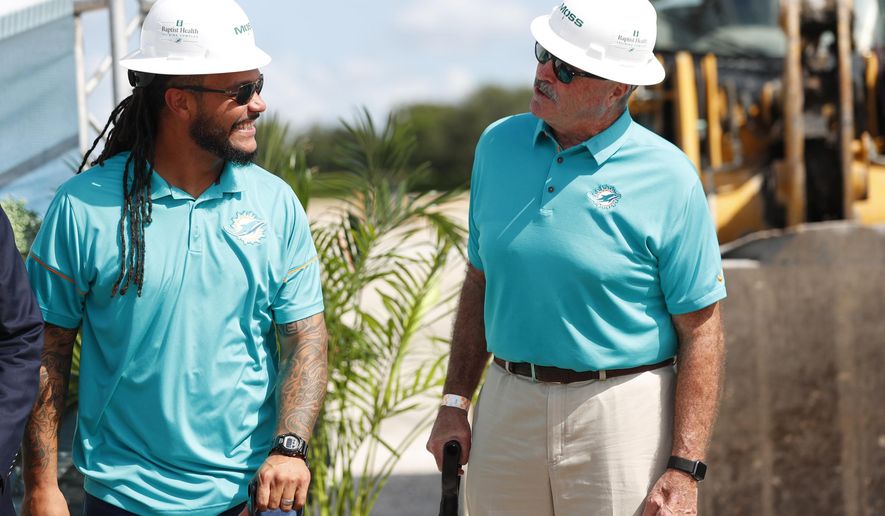 Former Miami Dolphins players Channing Crowder, left, and Kim Bokamper chat during a ground breaking ceremony for the teams new NFL football training facility, Wednesday, Aug. 21, 2019, in Miami Gardens, Fla. The Dolphins broke ground on a $135 million training complex and sports performance clinic next to Hard Rock Stadium where the team plays. (AP Photo/Wilfredo Lee)