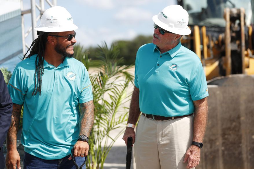 Former Miami Dolphins players Channing Crowder, left, and Kim Bokamper chat during a ground breaking ceremony for the teams new NFL football training facility, Wednesday, Aug. 21, 2019, in Miami Gardens, Fla. The Dolphins broke ground on a $135 million training complex and sports performance clinic next to Hard Rock Stadium where the team plays. (AP Photo/Wilfredo Lee)