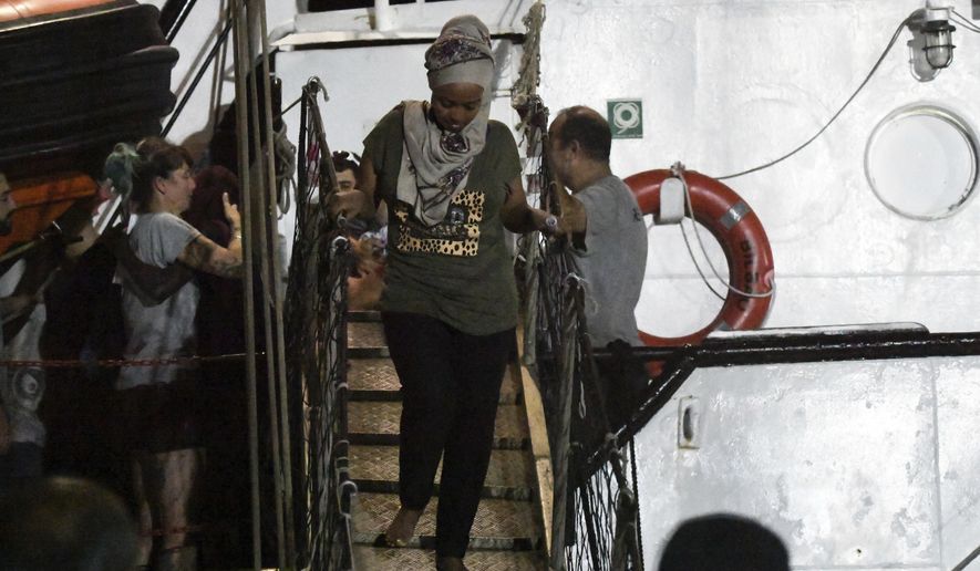 In this photo taken on Tuesday, Aug. 20, 2019, a woman disembarks from the Open Arms rescue ship on the Sicilian island of Lampedusa, southern Italy. An Italian prosecutor ordered the seizure of a rescue ship and the immediate evacuation of more than 80 migrants still aboard, capping a drama Tuesday that saw 15 people jump overboard in a desperate bid to escape deteriorating conditions on the vessel and Spain dispatch a naval ship to try to resolve the crisis. (AP Photo/Salvatore Cavalli)