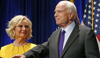 In this Tuesday, Nov. 8, 2016, file photo, Sen. John McCain, R-Ariz., right, pauses as his wife, Cindy McCain, looks at him on stage after giving his victory speech as he announces his win over Democratic challenger Rep. Ann Kirkpatrick, in Phoenix. The family of the late Sen. John McCain says they want to build a library on land donated by Arizona State University to house his archives and provide a “gathering place” for respectful dialogue. (AP Photo/Ross D. Franklin, File)