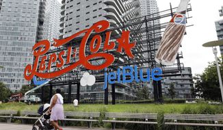 An LED lighted JetBlue logo has been added to the landmarked, neon-lit Pepsi-Cola sign in the Long Island City neighborhood of the Queens borough of New York, Wednesday, Aug. 21, 2019. The JetBlue name will remain until Oct. 1, part of a promotion to announce a partnership in which the airline will serve PepsiCo drinks. (AP Photo/Richard Drew)